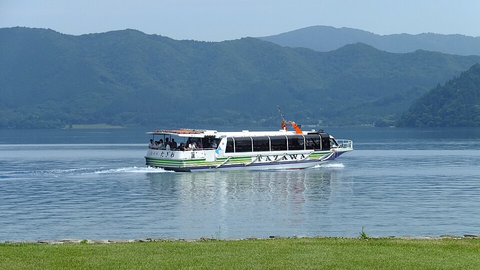 田沢湖（たざわこ）的遊覽船在湖面行駛，背景是秋田縣山巒景色——日本最深的湖