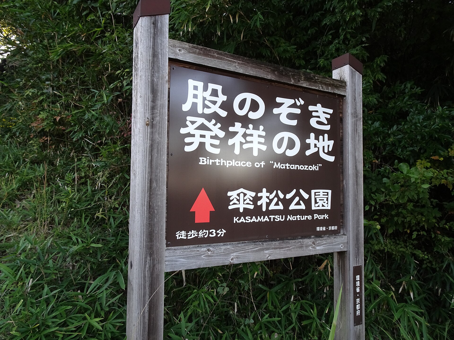 通往傘松公園的路上豎立的木製指示牌，寫著「股のぞき発祥の地（Birthplace of Matanozoki）傘松公園」與「徒歩約3分」