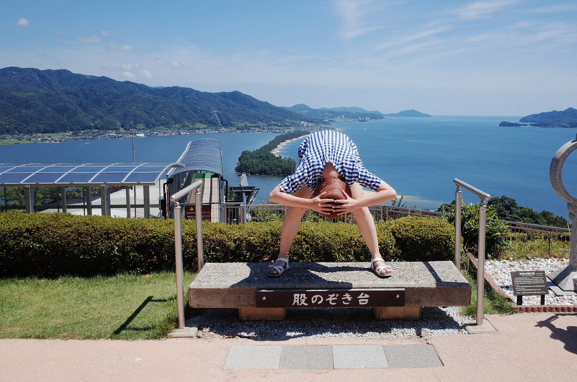 天橋立View Land 的「股のぞき台」石台，一名遊客站在台上彎腰從兩腿之間倒看天橋立砂洲