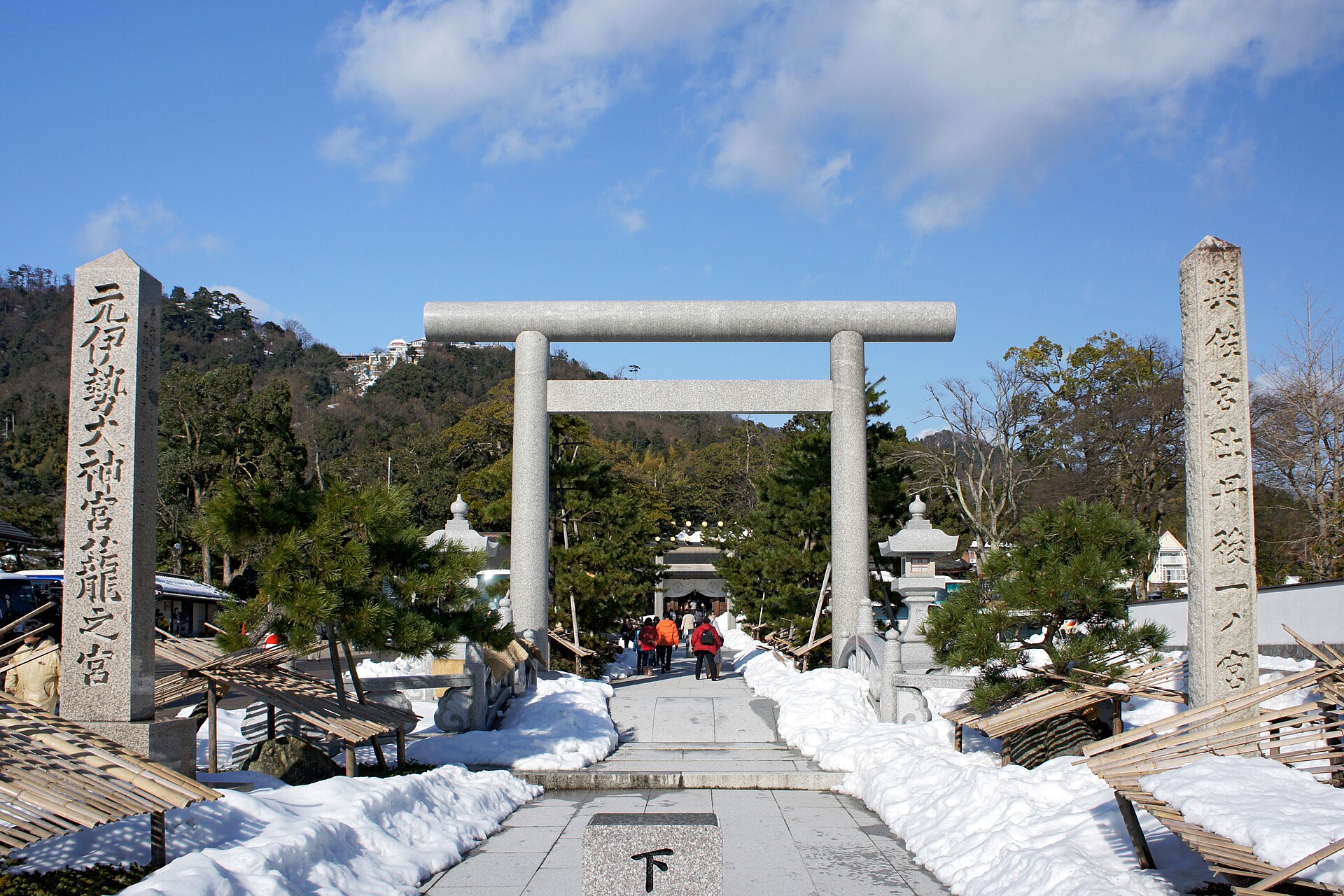 元伊勢籠神社的石造鳥居與參道，左側立著刻有「元伊勢大神宮 籠之宮」的石柱，地面與兩旁積雪