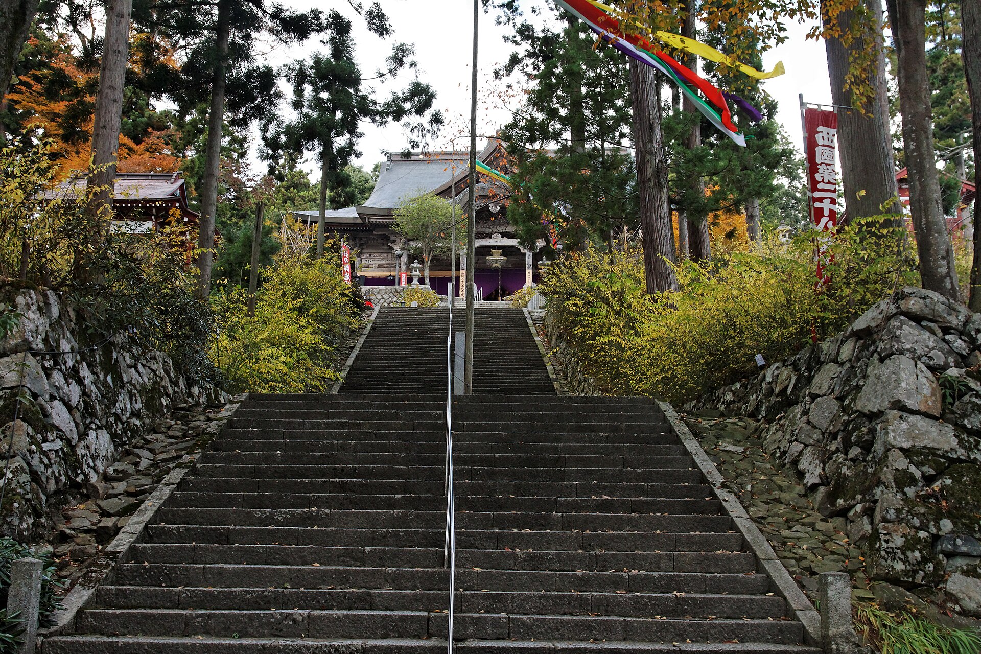 成相寺的石階參道，秋天時兩側樹葉轉黃，盡頭是掛著五色幡的本堂