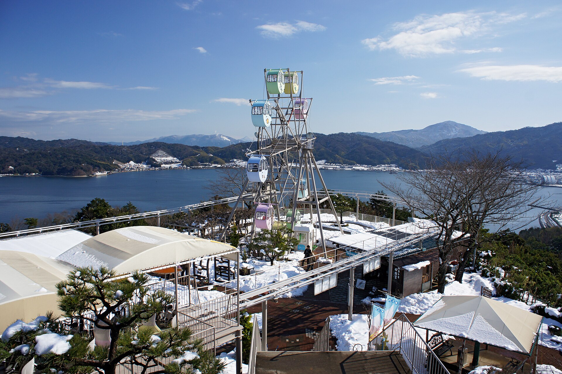 天橋立View Land 山上的小型摩天輪與遊樂設施，背景是冬季的阿蘇海與對岸山脈