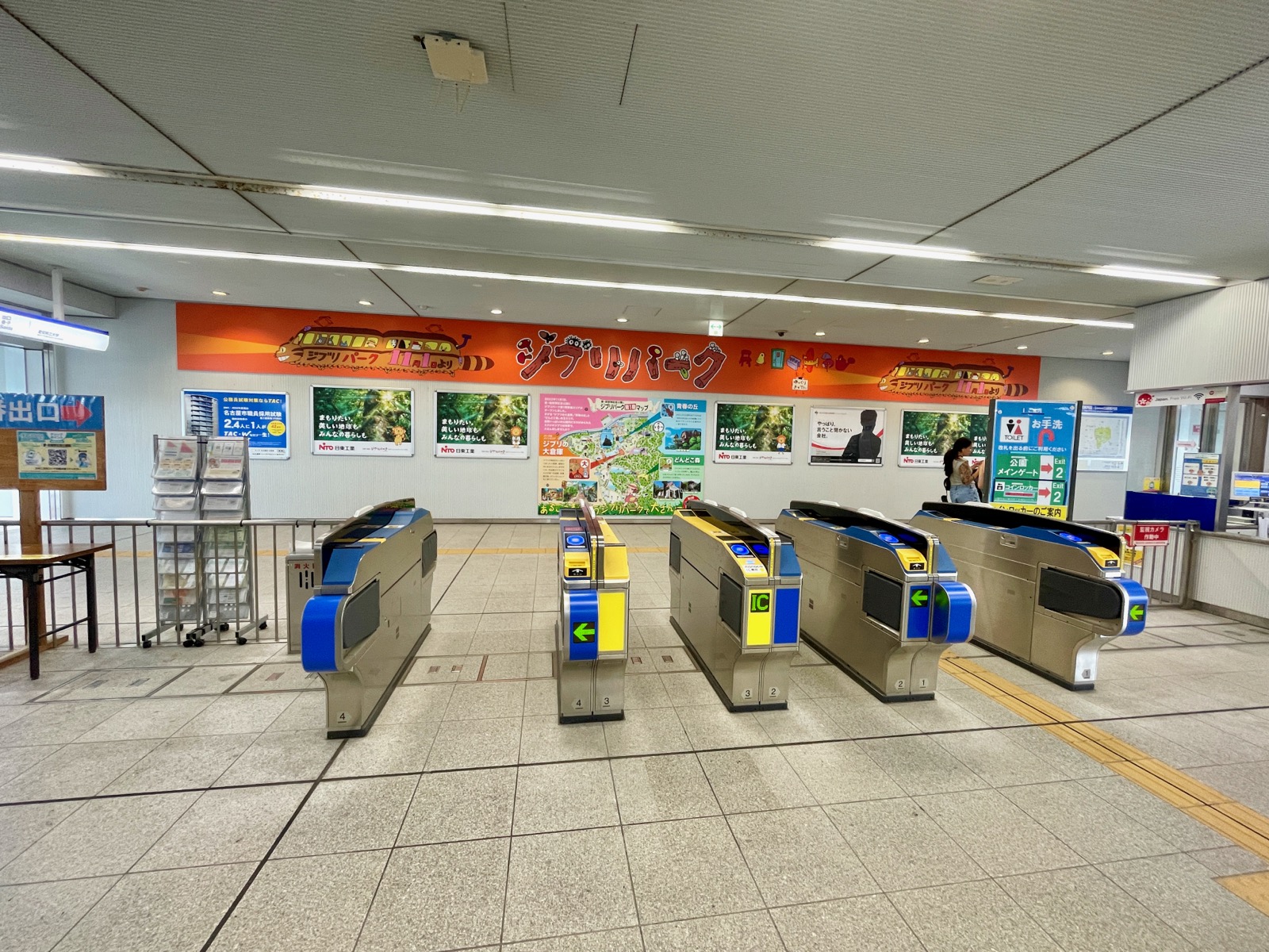 磁浮列車 Linimo「愛・地球博記念公園駅」剪票口 — 上方有橘色吉卜力公園看板與園區地圖海報