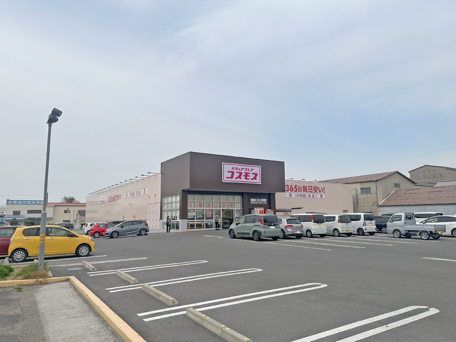 ドラッグストアコスモス（大藥妝）的郊區型店舖，茶色屋頂配紅色「365 日毎日安い」招牌與大型停車場