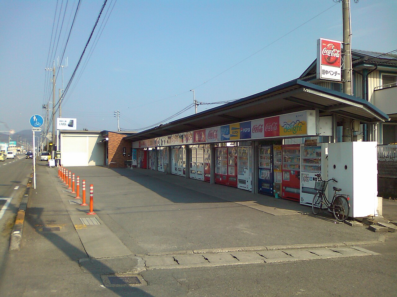 德島縣板野郡北島町路邊一整排的日本自動販賣機 —— 十幾台飲料機沿著屋簷一字排開，這種「自販機牆」是外國旅客最常拍下的日本日常風景之一