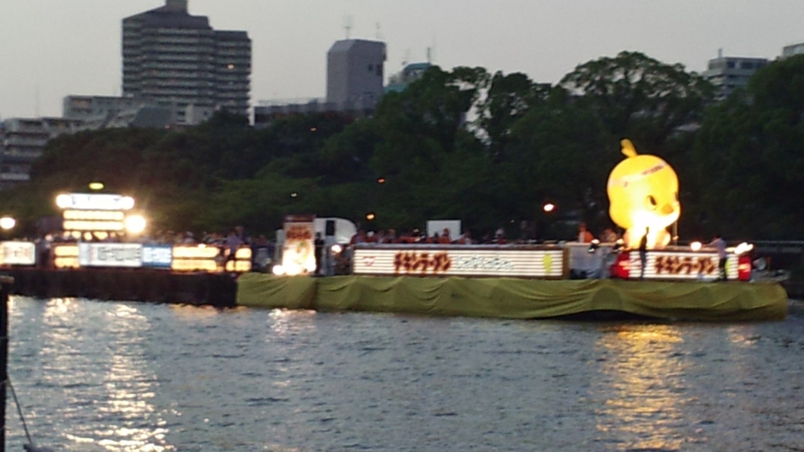 天神祭船渡御中的一艘奉納船，船上掛滿燈籠與旗幟，是「火與水之祭」的代表畫面