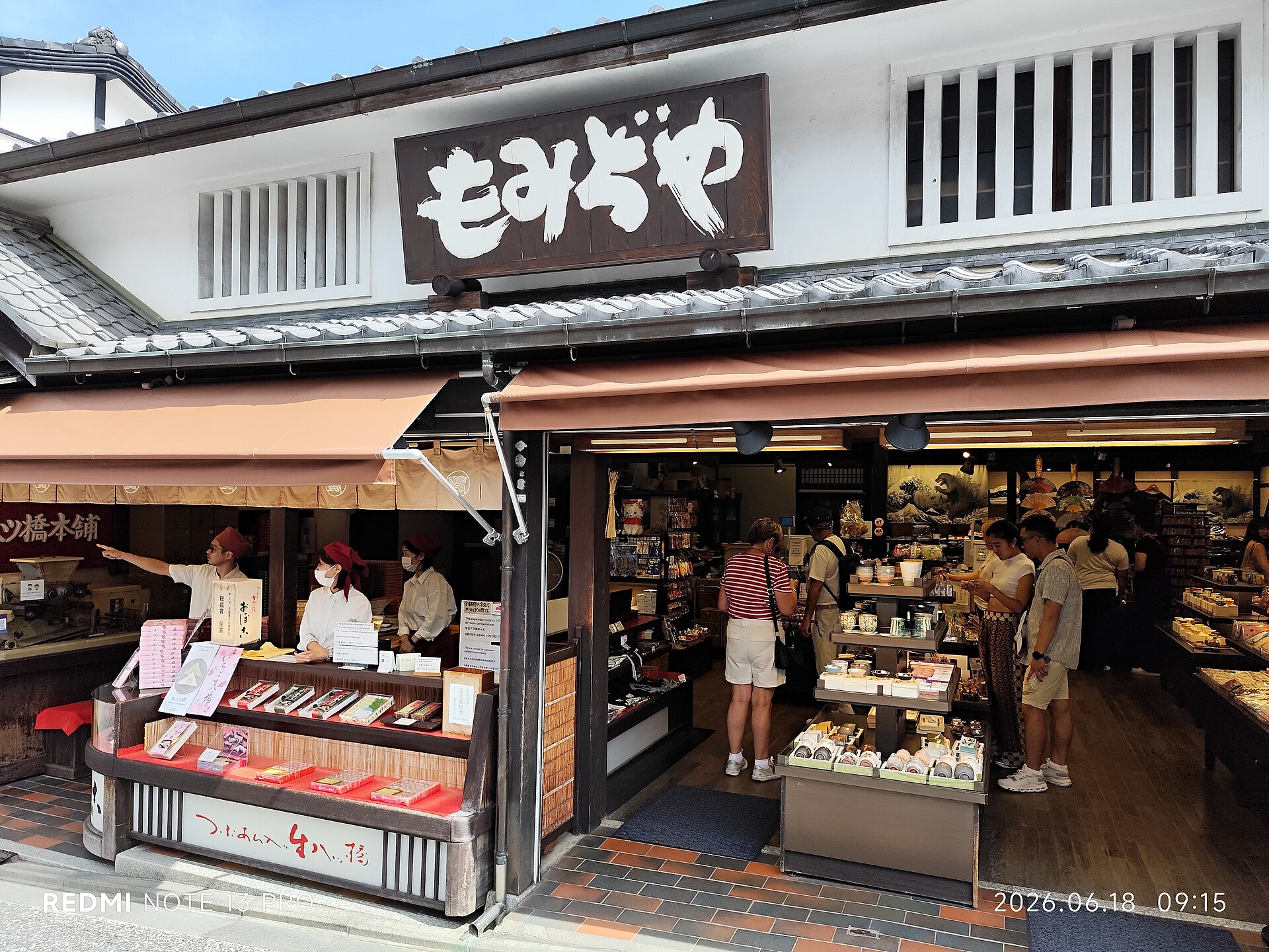 2026 年 6 月清晨的京都東山區觀光商店街，店家陸續開門，遊客沿著石板坡道往上走