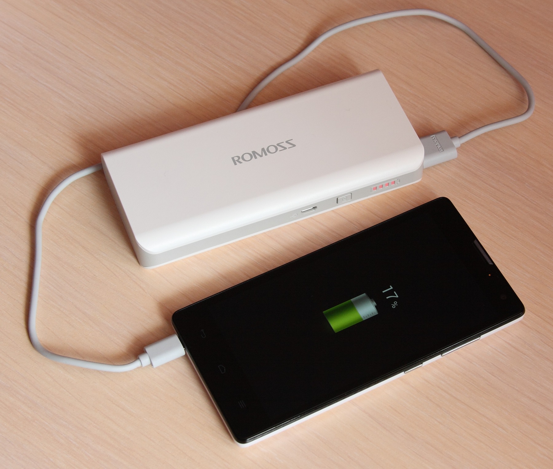 智慧型手機透過傳輸線連接行動電源充電的近拍照片
