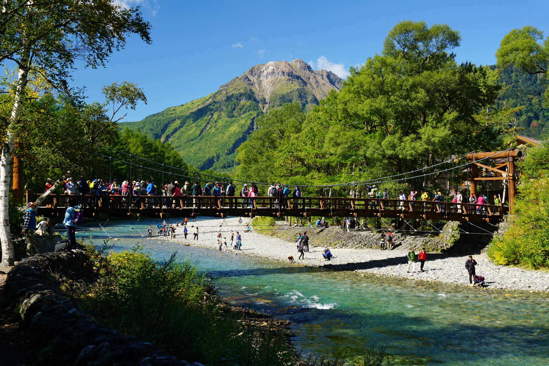 上高地河童橋吊橋，橋後方是穗高連峰的雪山全景